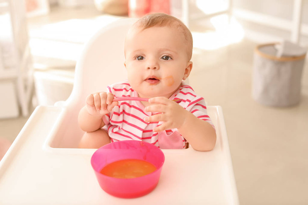Portrait of cute little baby eating tasty food in kitchen - Photo, image