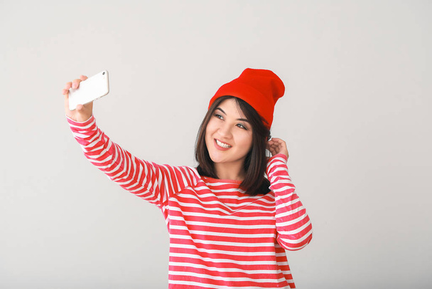 Güzel Asyalı genç bir kadının portresi açık arkaplanda selfie çekiyor. - Fotoğraf, Görsel