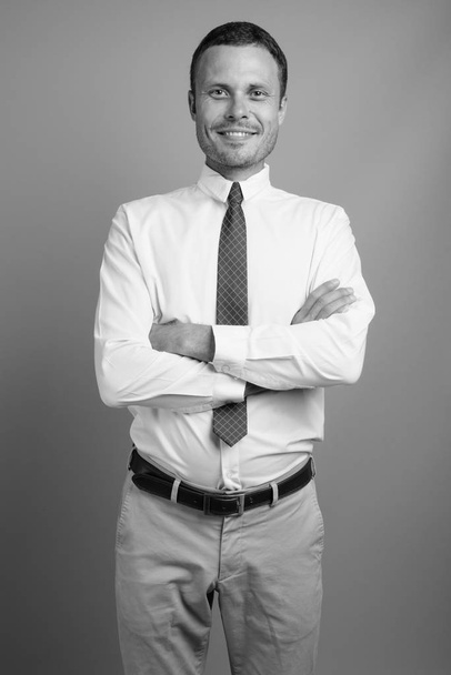 Portrait of handsome businessman against gray background - Foto, Imagen