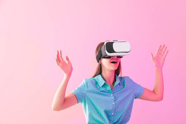 jonge vrouw met virtual reality bril op kleur achtergrond - Foto, afbeelding