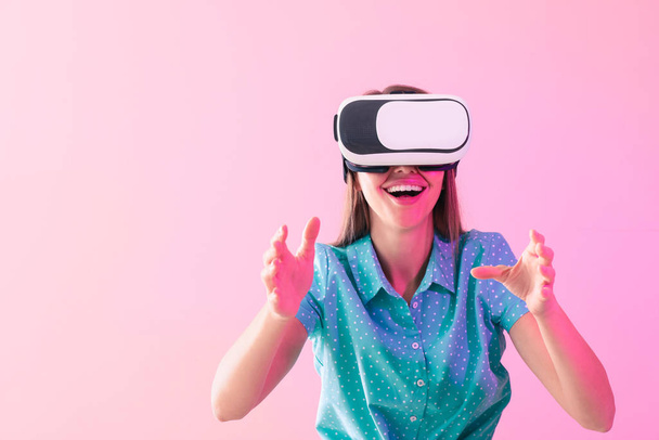 Mujer joven con gafas de realidad virtual sobre fondo de color - Foto, imagen