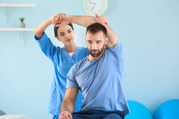 Physiothérapeute travaillant avec un patient masculin dans un centre de réadaptation
 - Photo, image