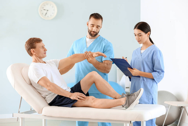 Fisioterapeutas que trabalham com pacientes do sexo masculino em centro de reabilitação
 - Foto, Imagem