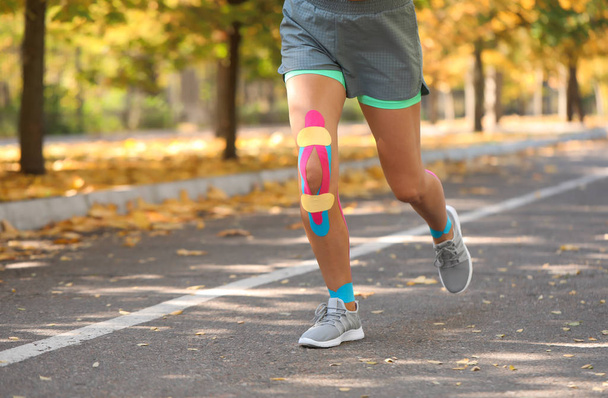 Αθλητική γυναίκα με ταινία σωματική διάπλαση τρέχει στο πάρκο - Φωτογραφία, εικόνα