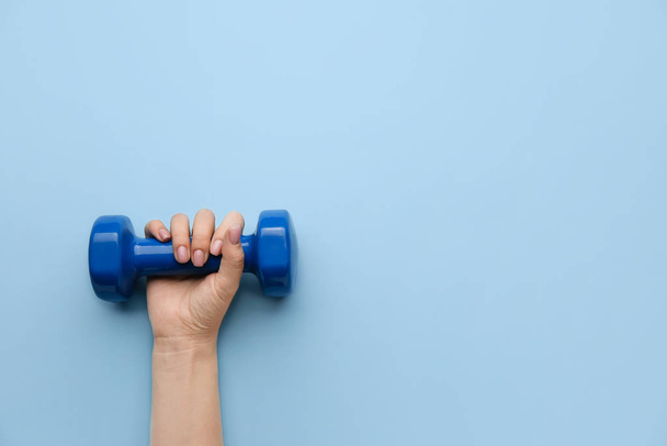 Female hand with dumbbell on color background - 写真・画像