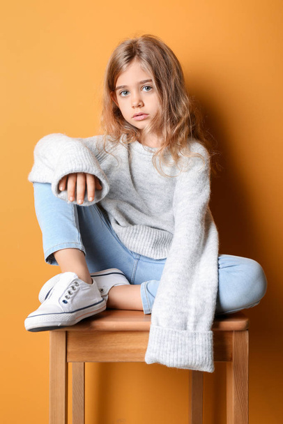 Cute fashionable girl sitting near color wall - Foto, afbeelding