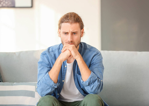 Uomo depresso seduto sul divano a casa
 - Foto, immagini