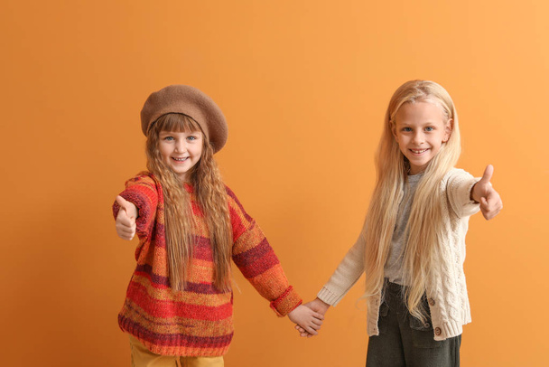 Söpö pikkutytöt syksyllä vaatteita osoittaa peukalo-up väri tausta
 - Valokuva, kuva