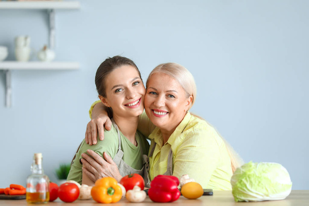 Mature woman and her adult daughter together in kitchen - Photo, Image