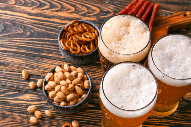 Gläser mit verschiedenen leckeren Bieren mit Snacks auf Holztisch - Foto, Bild