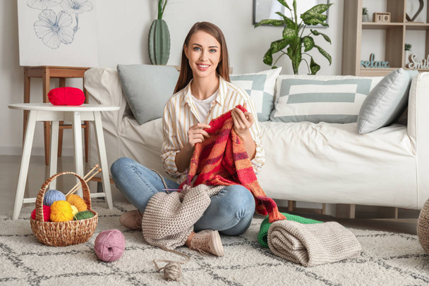 Young woman with finished knitted sweater at home - Foto, Bild