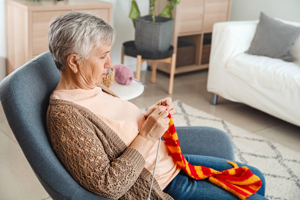 Senior woman knitting warm scarf at home - Foto, Bild