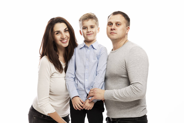 Parents with their son a schoolboy smiling, hugging and looking at the camera. A happy family. Love and tenderness. White background. - Φωτογραφία, εικόνα
