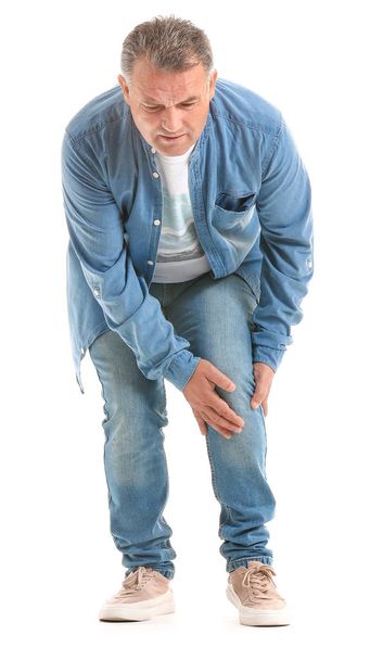 Mature man suffering from pain in knee on white background - Photo, Image