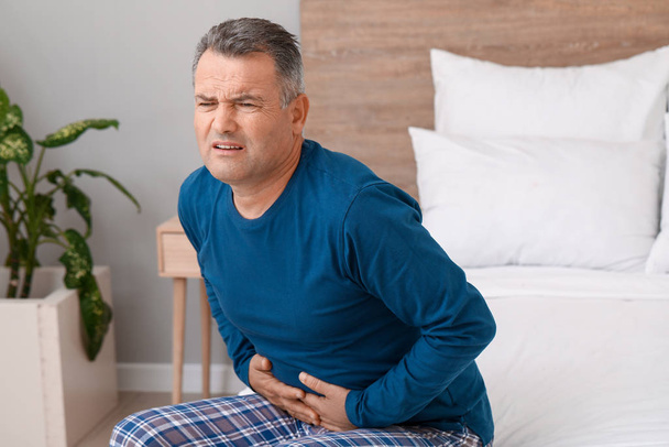 Dojrzały mężczyzna cierpiący na ból brzucha w sypialni - Zdjęcie, obraz