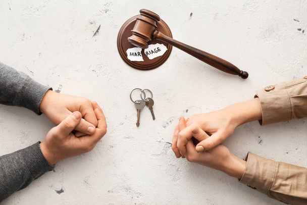 Hände eines Ehepaares mit Schlüsseln und Richtergabel auf weißem Hintergrund. Scheidungskonzept - Foto, Bild