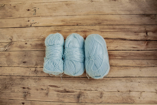 three skeins of thread for knitting light blue color lie on wooden boards - 写真・画像