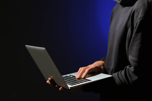 Hackeador profesional con portátil sobre fondo oscuro - Foto, imagen