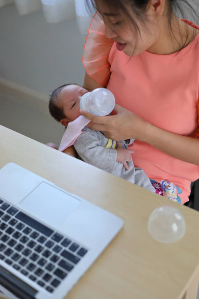 femme d'affaires qui allaite son bébé et travaille avec un ordinateur portable
 - Photo, image