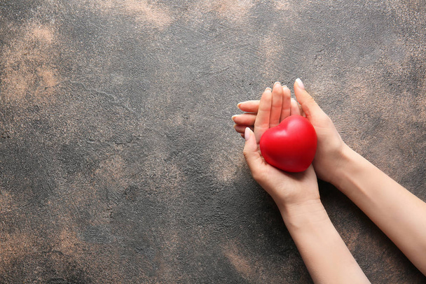 Female hands with heart on grunge background - Foto, Bild