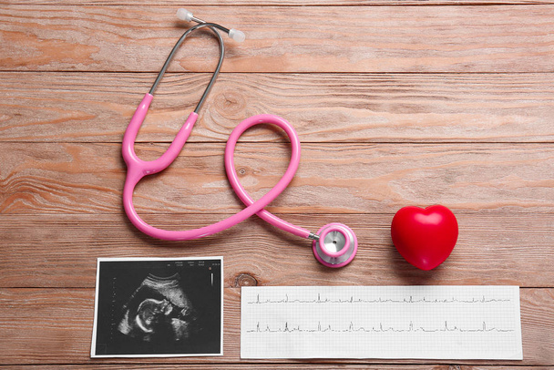 Stethoscope, heart, ultrasound image and cardiogram on wooden background - Photo, Image