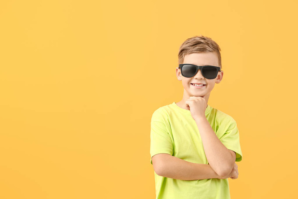 Roztomilý malý chlapec se slunečními brýlemi na barevném pozadí - Fotografie, Obrázek