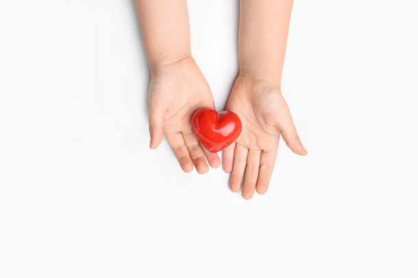 Dětské ruce s červeným srdcem na bílém pozadí. Koncepce kardiologie - Fotografie, Obrázek