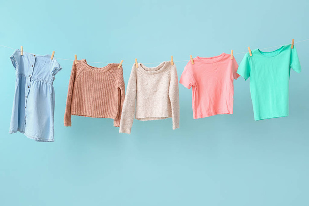 Clean laundry hanging on line against color background - 写真・画像