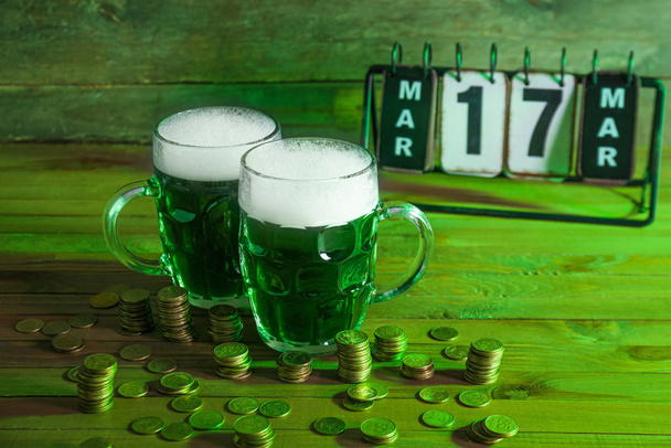 Aziz Patrick Günü için bir kupa yeşil bira ve ahşap masa üzerinde bozuk paralar. - Fotoğraf, Görsel