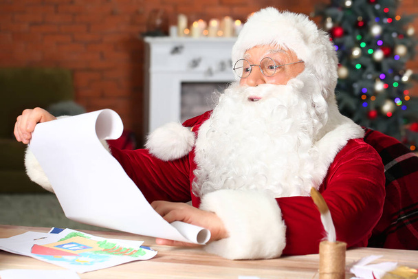 Άγιος Βασίλης ανάγνωση λίστα επιθυμιών στο δωμάτιο διακοσμημένα για τα Χριστούγεννα - Φωτογραφία, εικόνα