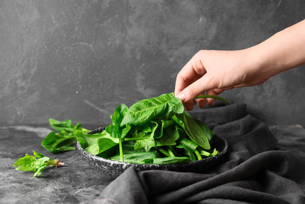 Woman with plate of fresh green spinach at table - Photo, Image
