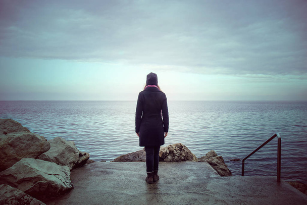 Вид сзади одинокой женщины, смотрящей на мир, концепция одиночества в зимний сезон - Фото, изображение