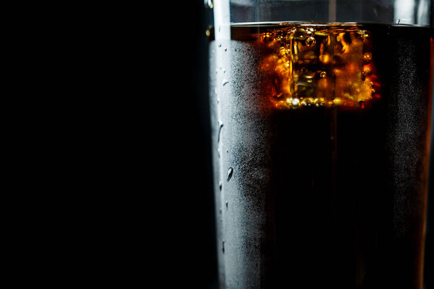 Soda in a glass on a black background with ice cubes and drops - Φωτογραφία, εικόνα