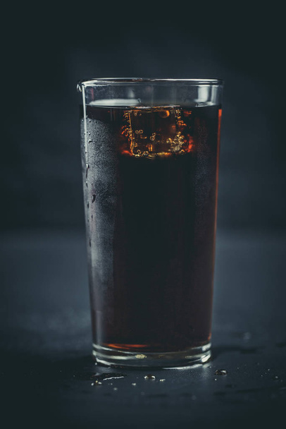 Soda in a glass on a black background with ice cubes and drops - Fotó, kép