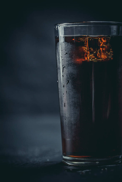 Soda in a glass on a black background with ice cubes and drops - Zdjęcie, obraz