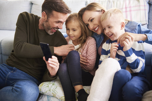 Familia usando el teléfono móvil en la sala de estar
  - Foto, Imagen