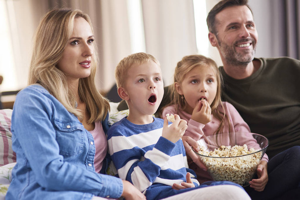 Семья с двумя детьми смотрят телевизор в гостиной
  - Фото, изображение