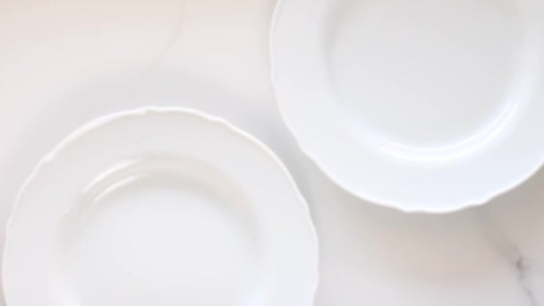 Puste białe talerze porcelanowe na marmurowym stole, dekoracje obiadowe stołowe płaskie układanki, top view food videography as recipe inspiration for cooking vlog or flatlay menu - Materiał filmowy, wideo