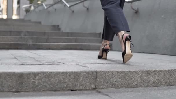 Επιχειρηματίας γυναίκα με κόκκινο σακάκι και μαύρο παντελόνι πλησιάζει στο επιχειρηματικό κέντρο με μια τσάντα στο χέρι της - Πλάνα, βίντεο