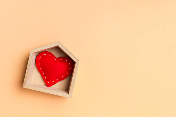 Vista superior del corazón textil rojo en una casa de madera sobre fondo colorido. Hogar dulce hogar concepto. Día de San Valentín - Foto, imagen
