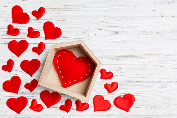 Bovenaanzicht van rood hart in een huis versierd met kleine hartjes op houten achtergrond. Valentijnsdag. Huis zoete home concept - Foto, afbeelding