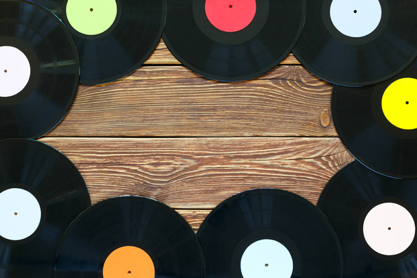 Retro vinyl discs records on wood table background. Multicolored labels. Top view. Place to copy space. - Photo, Image