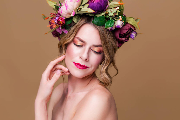 hermosa joven modelo con flores brillantes en la cabeza en el fondo de color ocre
 - Foto, Imagen