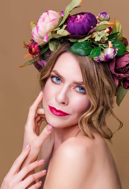 hermosa joven modelo con flores brillantes en la cabeza en el fondo de color ocre
 - Foto, Imagen