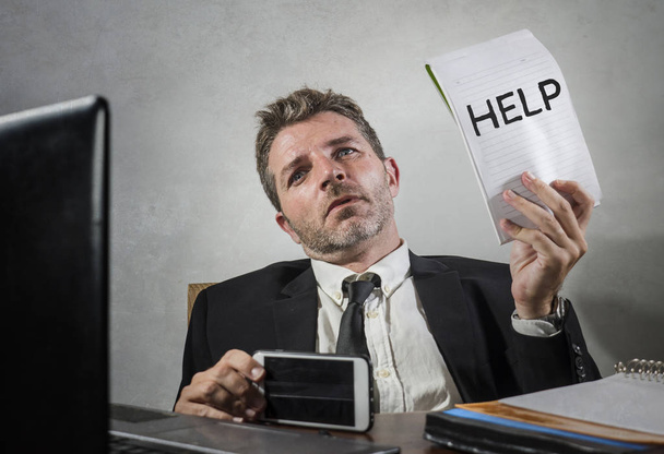 üzleti életmód portré depressziós és túlterhelt vonzó férfi dolgozik irodai számítógép íróasztal a stressz tartó jegyzettömb, mint a segítség jele érzés frusztrált és kimerült - Fotó, kép