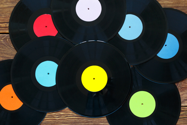Retro-Schallplatten auf Holztischhintergrund. Bunte Etiketten. Ansicht von oben. - Foto, Bild