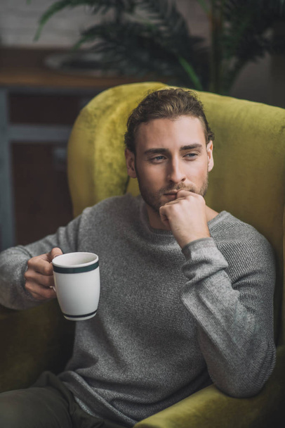 Young bearded handsome man with cup looking thoughtful - Foto, Bild