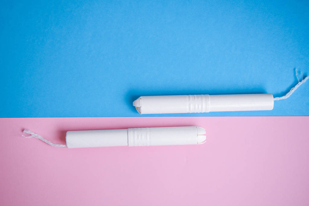 Hygiënische tampons op een blauwe en roze achtergrond. kopieerruimte, menstruatie sanitaire tampon voor vrouwelijke hygiëne bescherming. Kritieke dagen. Medische conceptie - Foto, afbeelding