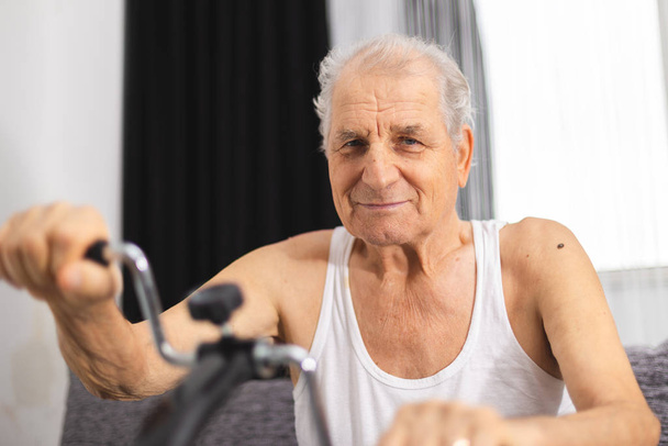 Senior man maken fysiotherapie voor gewrichten in de handen bij een huis medisch hulpmiddel - Foto, afbeelding