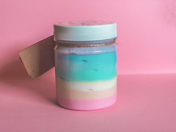 Bottle with body lotion of rainbow colors on a pink background. Body lotion, face and body cream. Cream with fashionable rainbow colors. The concept of care and beauty. Application in the beauty industry. - Photo, Image